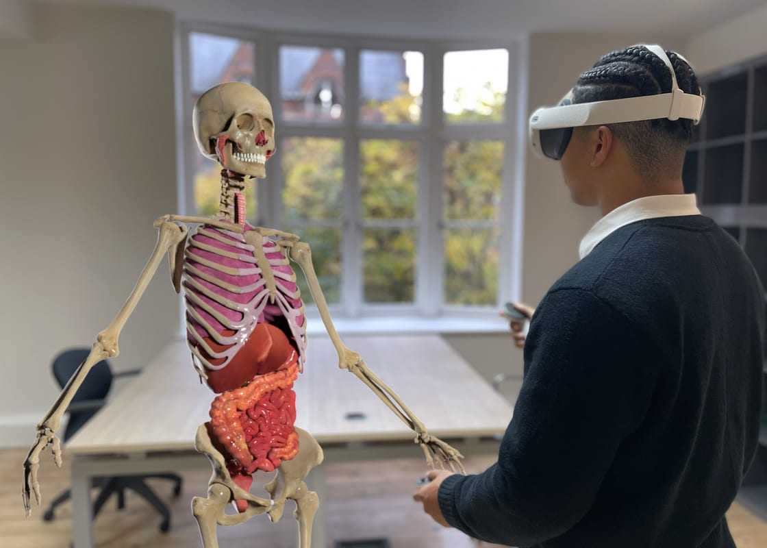 A student wearing a mixed-reality headset examines a life-size holographic human anatomy model.