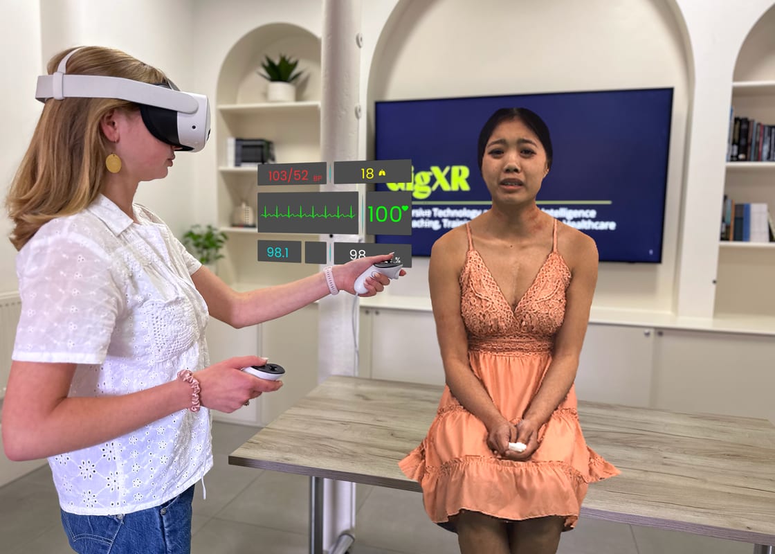 A student wearing a mixed-reality headset assesses a holographic standardized patient as live vital signs are displayed.